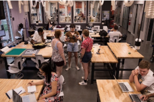 A makerspace with many desks and tables and students standing around them